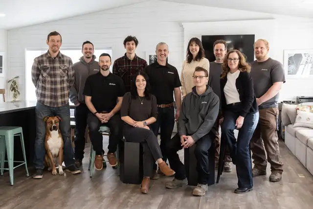 The Straight Line Design and Remodeling team standing together in a finished kitchen with their dog