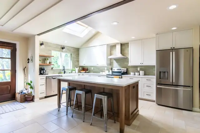 West Linn kitchen remodel with skylight, wood island with metal stools, white cabinets and stainless refrigerator