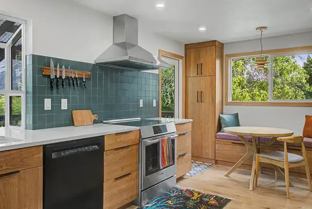 Southwest Portland kitchen with teal tile backsplash, stainless chimney hood, wood cabinets and a built-in breakfast nook