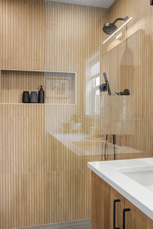 Portland basement bathroom remodel with vertical wood-look slat tile wall, glass shower and black fixtures