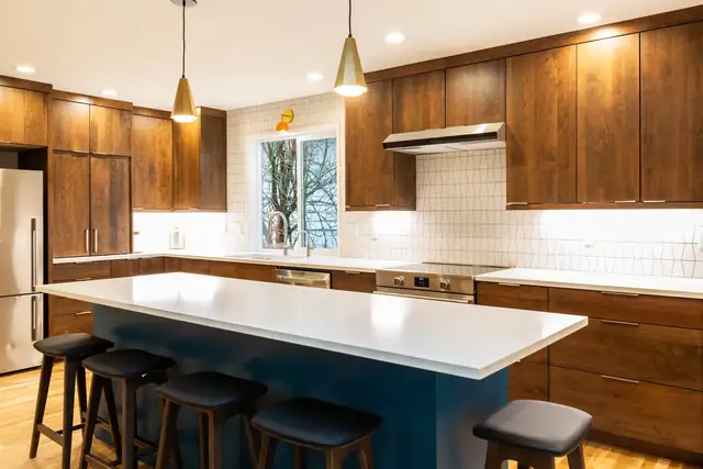 Southwest Portland kitchen with navy island, white quartz top, warm wood cabinets and brass pendant lights