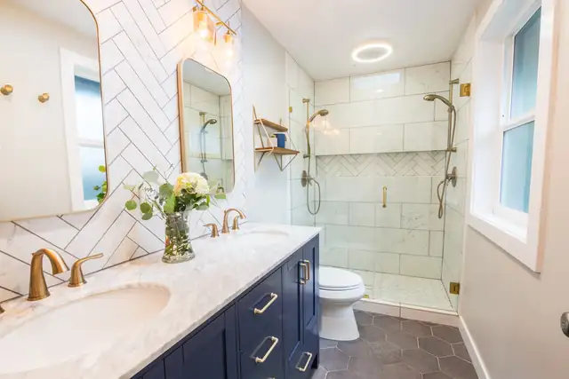 Lake Oswego bathroom remodel with navy vanity, white herringbone tile wall, brass faucet and frameless glass shower