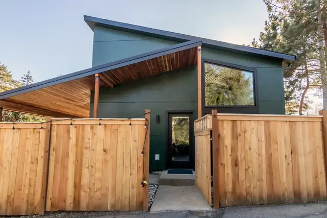 Portland ADU with dark green siding, shed roof, covered wood entry and horizontal cedar fence