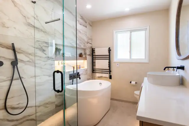Portland bathroom remodel with large-format marble-look shower walls, freestanding tub and black hand shower